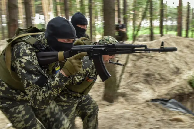 A few Ukrainian soldiers run with guns