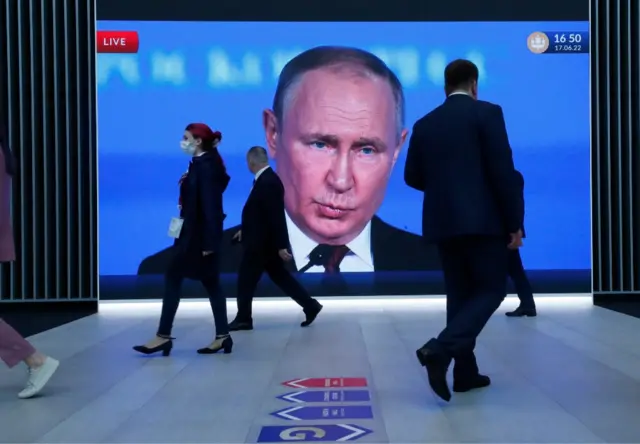 Vladimir Putin's face appears on a big screen