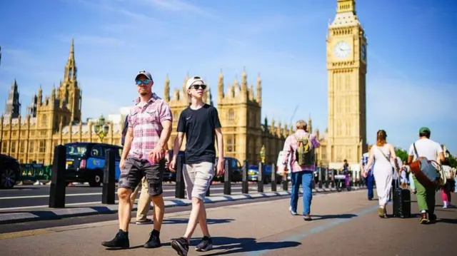 Tourists walk through London on a hot day