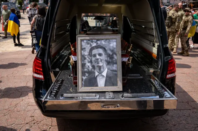 A photograph of Roman Ratushnyi sits on his hearse in Kyiv