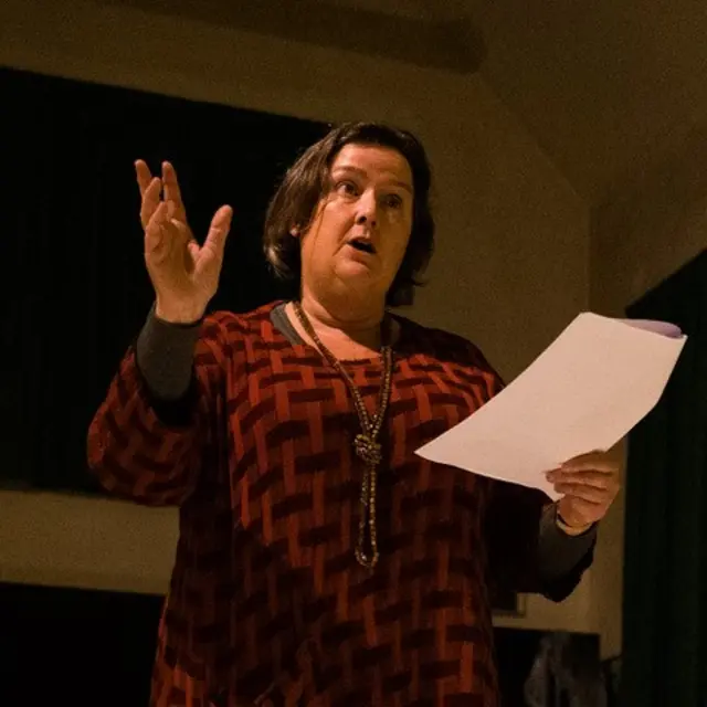 Clare Reddaway speaking to a crowd holding a piece of paper.