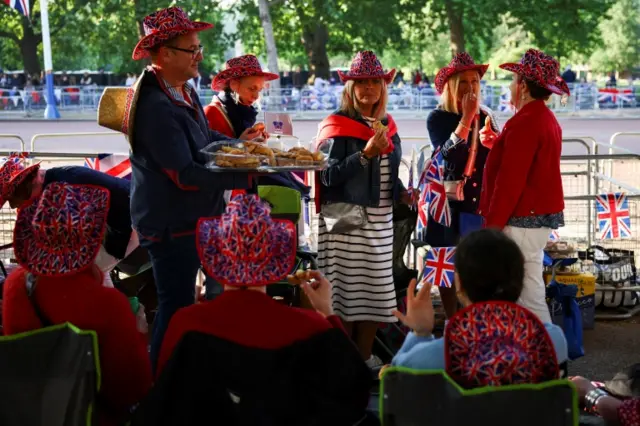 A man distributes food as people gather along The Mall for the Queen"s Platinum Jubilee celebrations