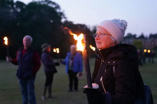 A woman holds a flaming torch at Sandringham, Norfolk