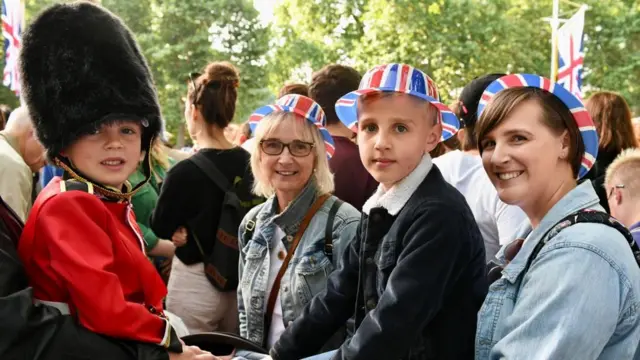 Member of the public Lucy Lyon is pictured with her young sons - one of who is dressed as a guardsman - and her own mother