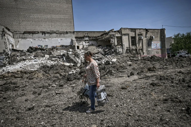 A woman walks past a destroyed building in Lysychansk, eastern Ukraine. Photo: May 2022