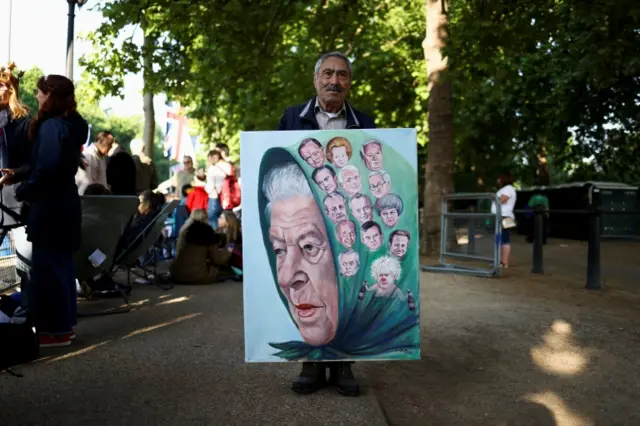 Satirical artist Kaya Mar poses with one of his artworks as people gather along The Mall for the Queen"s Platinum Jubilee celebrations in London, Britain June 2, 2022. REUTERS/Tom Nicholson NO RESALES. NO ARCHIVES