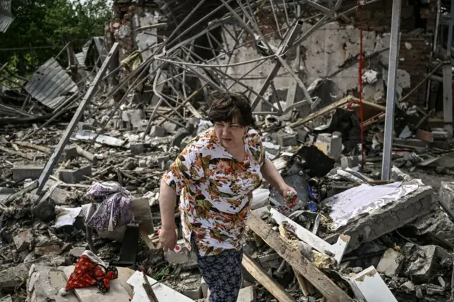 A woman looks for belongings in the rubble of her house after in the eastern city of Slovyansk