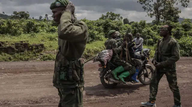 A motorcyclist carries soldiers as others patrol the area in Kibumba that was attacked by M23 rebels