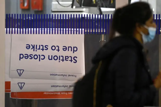 A passenger walks past a travel information message, ahead of a planned national strike by rail workers