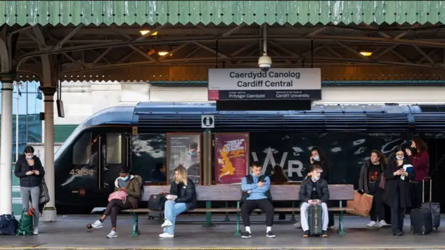 Commuters waiting at a station platform in Cardiff