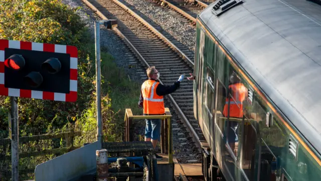 A signalman presents a key to the train driver