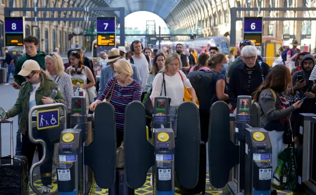 Passengers at ticket barriers as they arrive at London King's Cross station