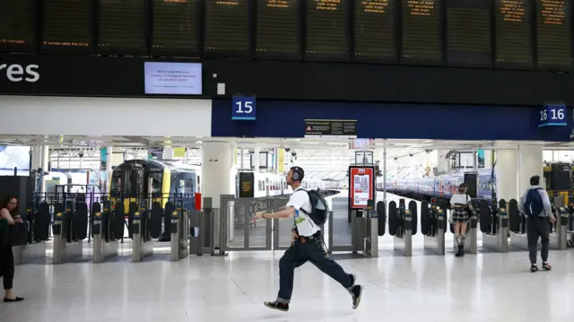 A passenger runs to catch a train at Waterloo station before train service ends early