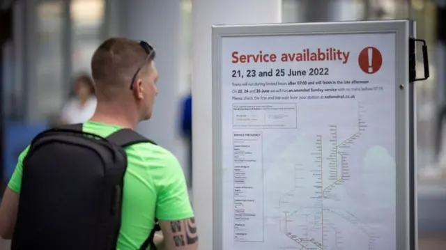 Man reads poster board warning of rail service disruption