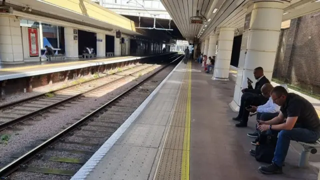 Commuters wait at a platform at London Fenchurch Street