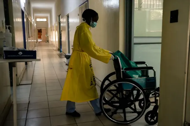 A nurse pushes a wheel chair along a corridor in a medical ward at a local hospital in Harare, in April 2022.