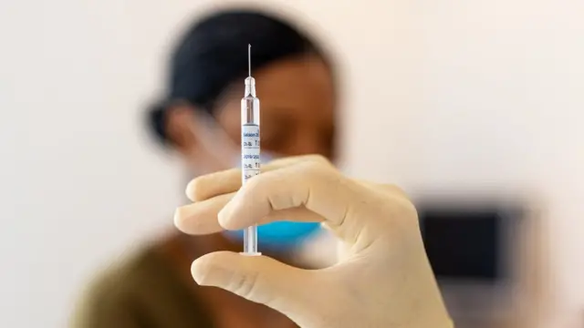 A medic holds a syringe before injecting a patient.