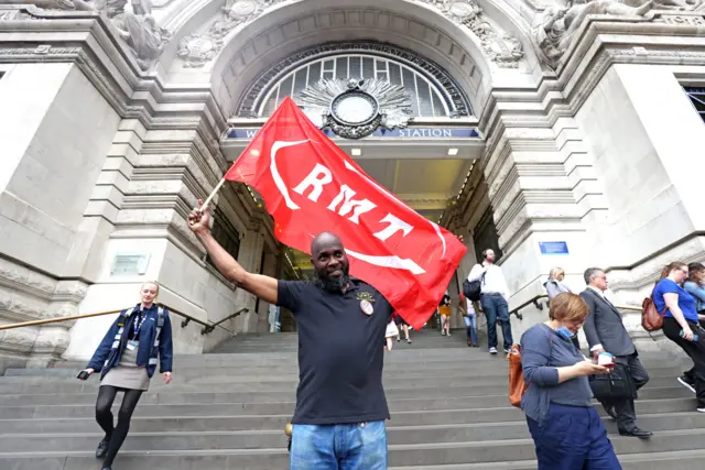 Man holding RMT flag outside Waterloo Station