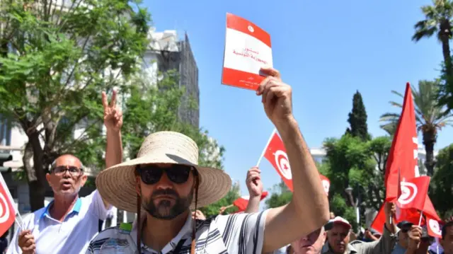 A protester holds the constitution booklet during a march in protest against the Tunisian President Kais Saied.