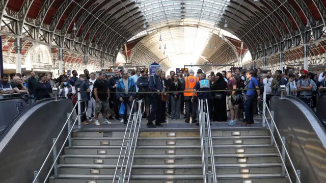 Passengers wait at Paddington station in London