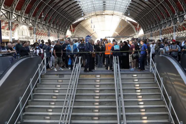 Passengers wait at Paddington station in London