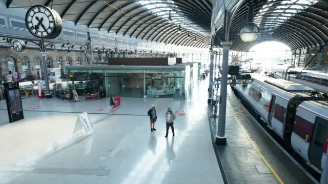 Two passengers stand in an almost deserted Newcastle station