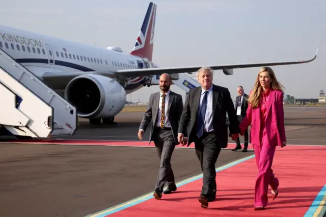 British PM Boris Johnson and his wife Carrie Johnson walk after disembarking from their plane as they arrive for the Commonwealth Heads of Government Meeting, in Kigali, Rwanda