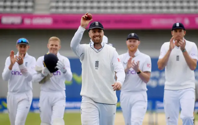 Jack Leach holding up the ball as he walks off to applause from the crowd and his team-mates