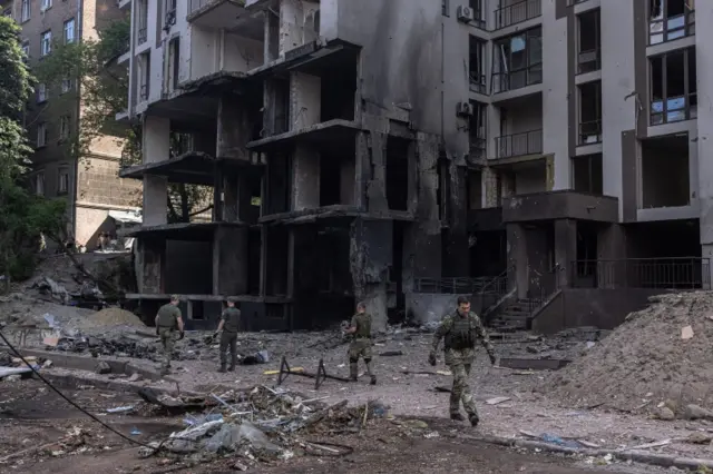 Ukrainian military members collect pieces of a missile on a site following Russian airstrikes