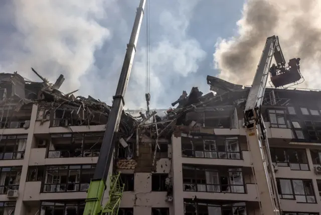 Rescuers in action next to a damaged residential building following Russian airstrikes in the Shevchenkivskiy district of Kyiv