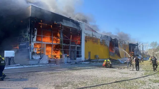 Firefighters tackle the fire at the Kremenchuk shopping centre