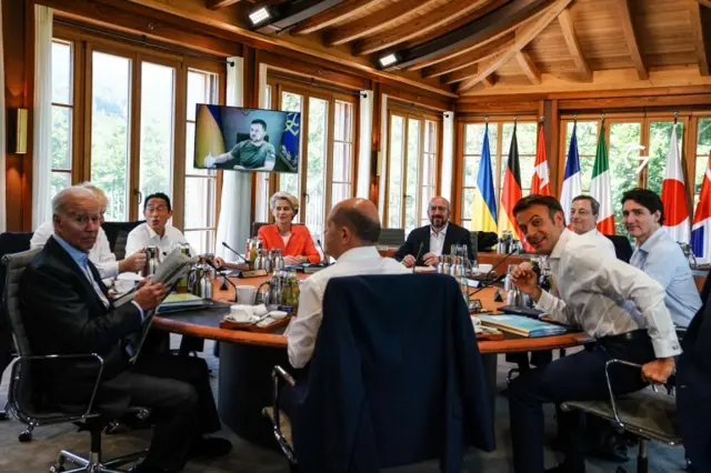 G7 leaders (L-R) US President Joe Biden, Japanese Prime Minister Fumio Kishida, European Commission President Ursula von der Leyen, German Chancellor Olaf Scholz, European Council President Charles Michel, French President Emmanuel Macron, Italian Prime Minister Mario Draghi and Canadian Prime Minister Justin Trudeau pose for a photo prior to an address by Ukrainian President Volodymyr Zelensky (on screen) via video link during the G7 Summit in Germany