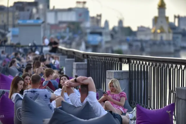 People spend the evening outdoors in a bar at the banks of Dnipro river