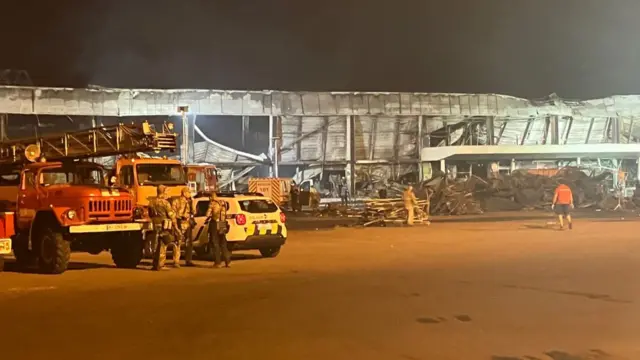 People outside the wreckage of a shopping center in Kremenchuk