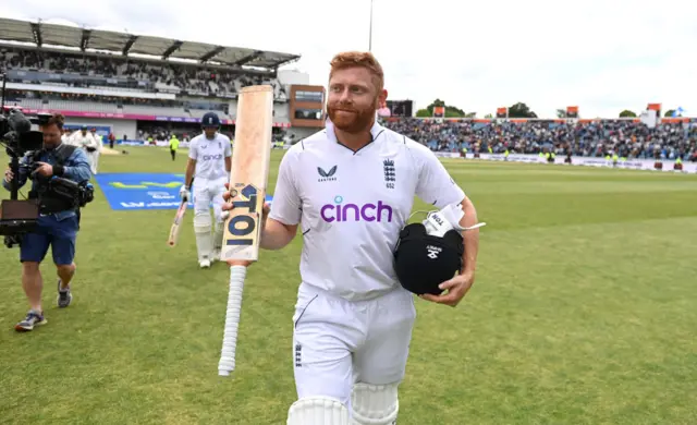 Jonny Bairstow holds his bat up to the crowd as he walks off the field