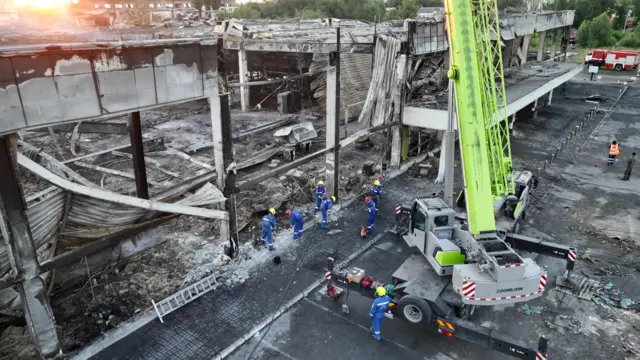 Rescue workers at a site of the shopping mall hit by a Russian missile strike in Kremenchuk, Ukraine