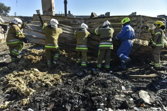 Firefighters clear the rubble of the destroyed Amstor shopping mall in Kremenchuk