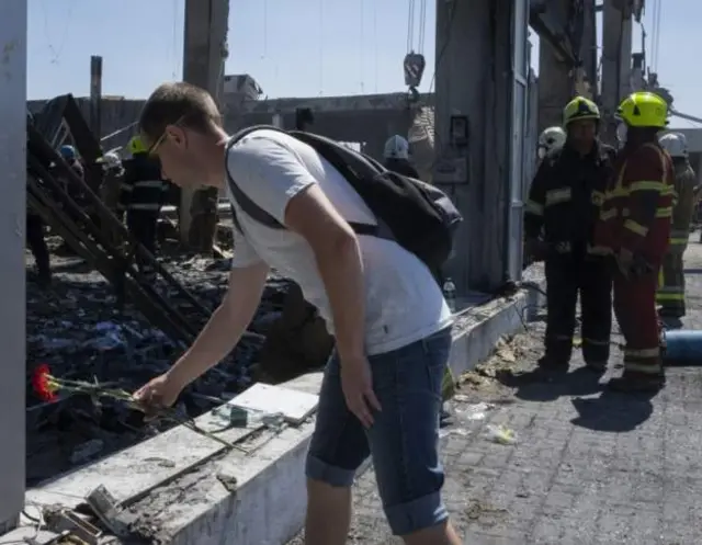 Man laying a flower at missile attack site