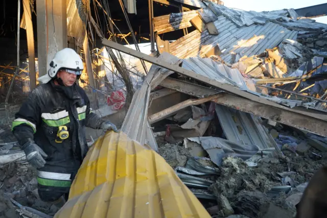 A rescuer works at a site of a shopping mall hit by a Russian missile strike in Kremenchuk, Ukraine