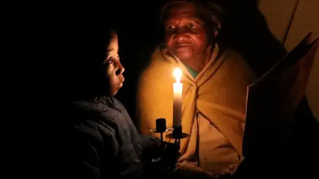 A woman and her great-grandson sit in candlelight during a power cut in 2021.