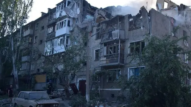 A rescuer stands next to a residential building hit by a Russian military strike in Mykolaiv