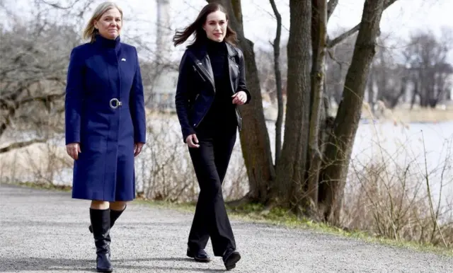 Swedish PM Magdalena Andersson and Finnish PM Sanna Marin walk next to a river