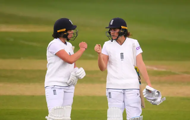 Alice Davidson-Richards (left) and Nat Sciver (right) bump fists as they leave the pitch