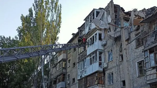 A rescuer helps a man to be evacuated from a residential building in Mykolaiv