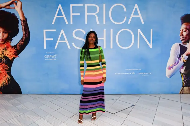 Woman standing in front of a sign saying "African Fashion"