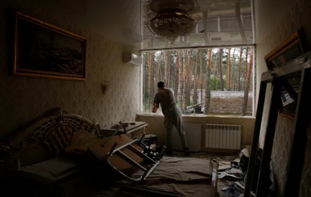 A man installs new windows in an apartment destroyed by Russia's attacks on Irpin, outside Kyiv