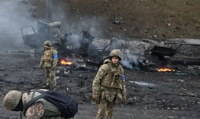 Ukrainian service members look for and collect unexploded shells after a fighting with Russian raiding group in the Ukrainian capital of Kyiv in the morning of February 26