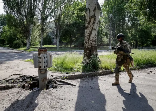 A Ukrainian soldier walks near a shell of a multiple rocket launch system in Lysychansk