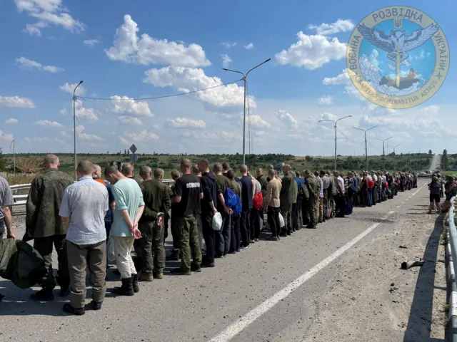 Prisoners line up alongside a road during a prisoner exchange