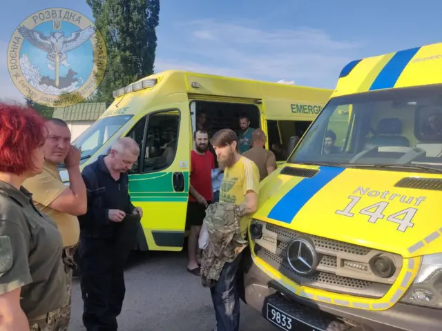 Ukrainian soldiers stand next to ambulances as Ukraine carries out an exchange of prisoners